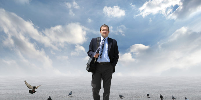 Man in suit walking toward camera with birds in background