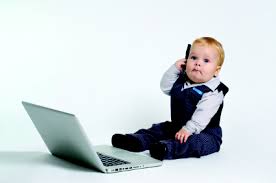 Baby holding phone in front of laptop
